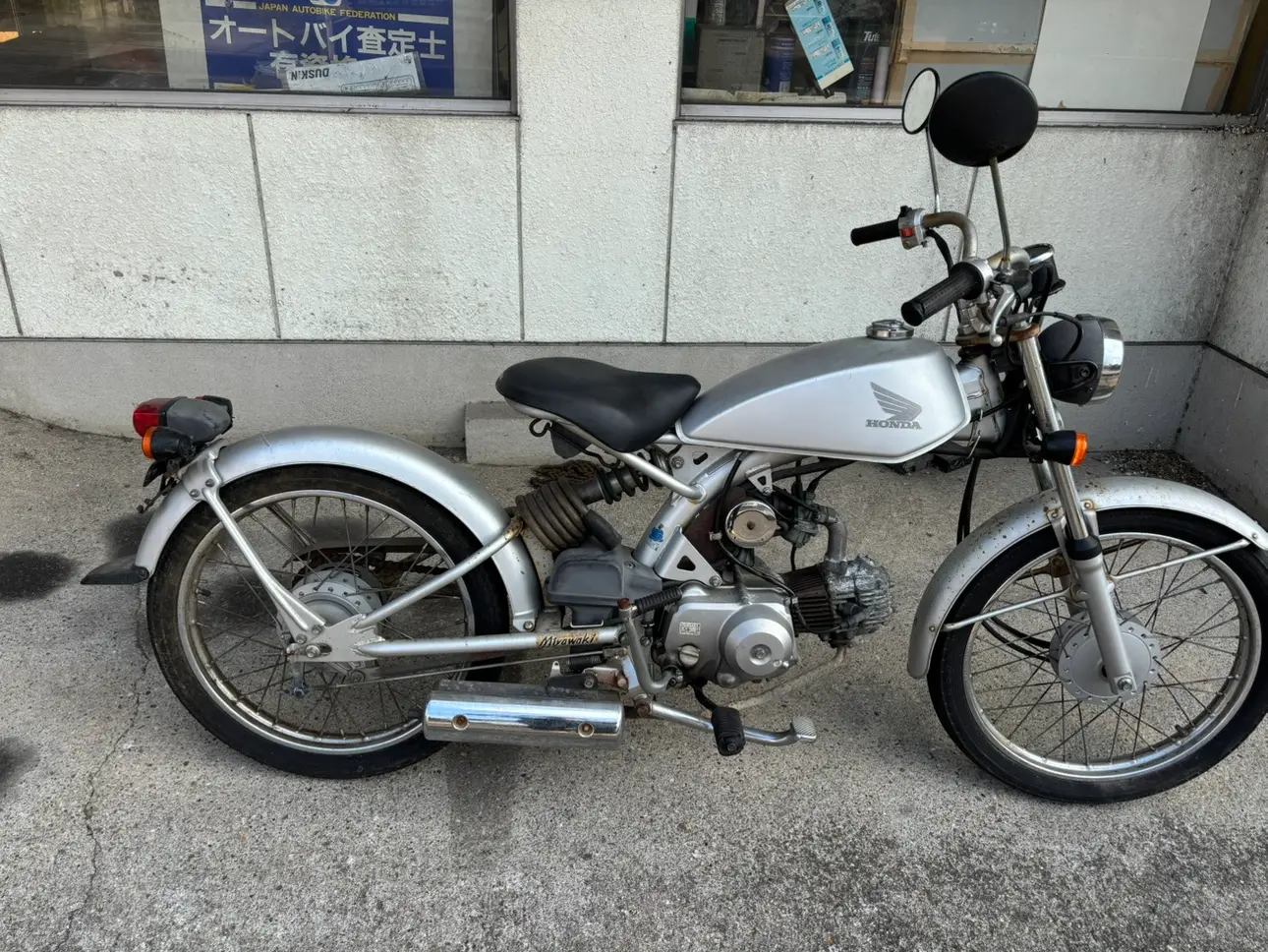 店先に置かれたシルバーの小型バイクの側面