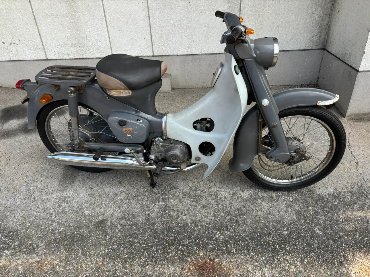グレーのスーパーカブ C65の側面。レッグシールドとロングシートがある