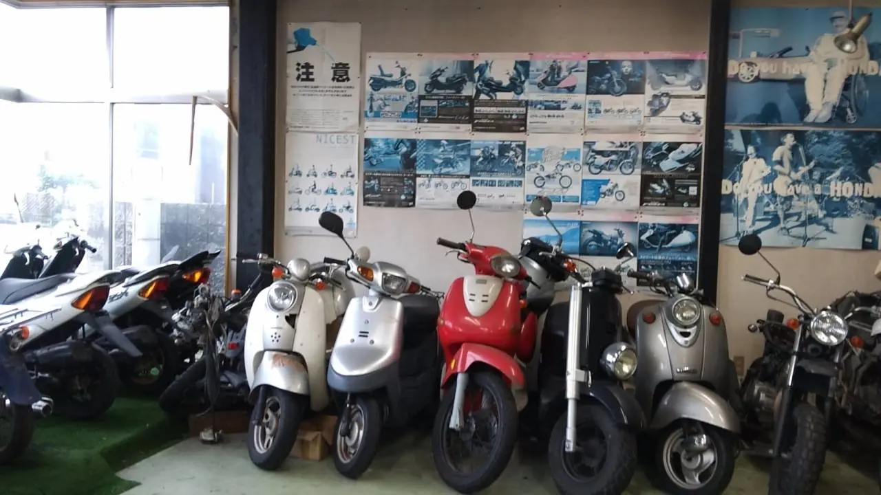 店内にスクーターが並んでいる。奥の壁にはバイクのカタログが貼ってある